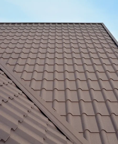 Metal roof construction with coaxial chimney pipe heating system against blue sky.