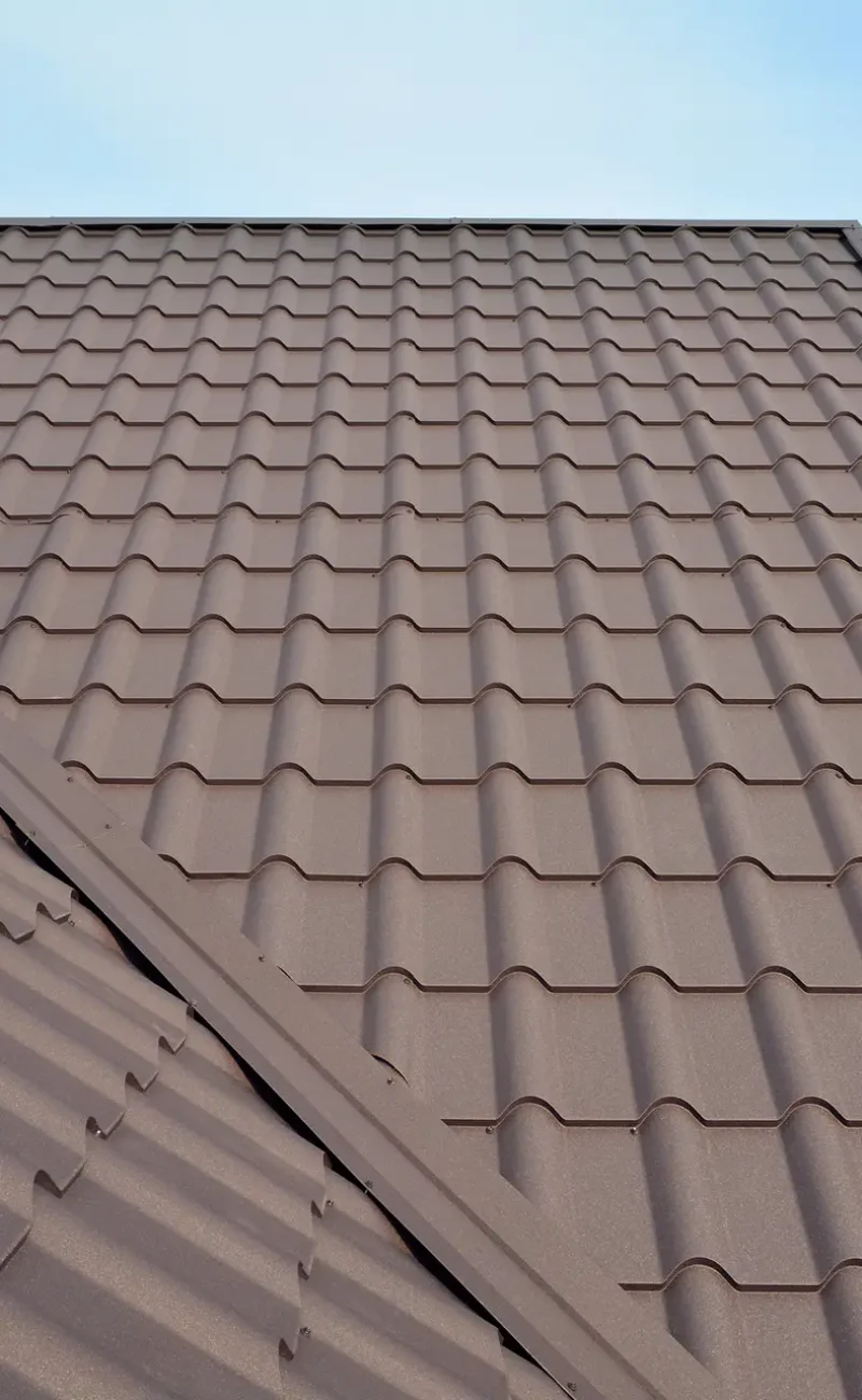 Metal roof construction with coaxial chimney pipe heating system against blue sky.