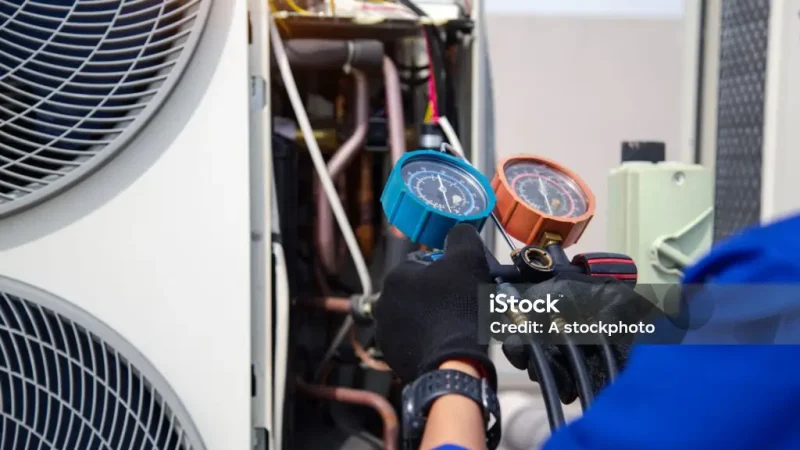 Air conditioner service .The air conditioner technician is using a gauge to measure the refrigerant pressure. air compressor.